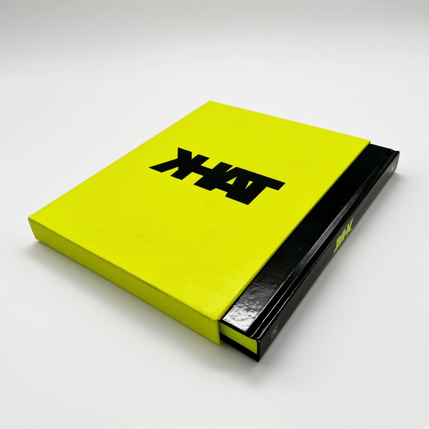Bright yellow book slipcase with black varnished lettering and a black book inside